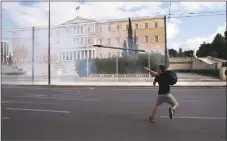  ?? Petros Giannakour­is / Associated Press ?? A young man throws a sign at riot police during a protest in central Athens on Monday. Greek police have fired tear gas to repel rioting teenagers who attacked them with petrol bombs and stones during a protest against the left-led government’s education policies.