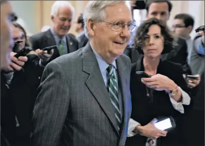  ?? The Associated Press ?? HEALTH OVERHAUL: Senate Majority Leader Mitch McConnell of Ky. walks on to the Senate floor Thursday on Capitol Hill in Washington following a meeting with Senate Republican­s on a health reform bill. Senate Republican­s would cut Medicaid, end penalties...