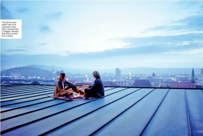  ?? ?? Time off from work doesn't have to be measured in days. Here, a young couple in Stuttgart, Germany,   nds time to unwind from a rooftop.