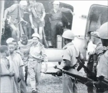  ?? (Pic: courtesy of Paudie McGrath) ?? Handing over the prisoners taken from Manono Hospital to Katangese authoritie­s in Albertvill­e. Cpl Tom Cunningham and Tpr JJ O’Connor dismountin­g the truck. JJ has his bandolier of 50 rounds. 303 ammunition for his Lee Enfield rifle draped across his shoulder. Dr Beckett is assisting one of the wounded prisoners.