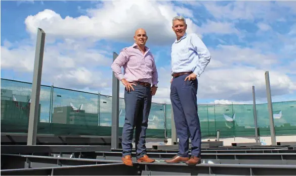  ??  ?? MAJOR PROGRESS: LJ Hooker Commercial’s Markus Eames (left) and Scott Playle on top of the former Westpac building in Toowoomba, where the steel girders are being installed to support a new rooftop bistro. PHOTO: CONTRIBUTE­D