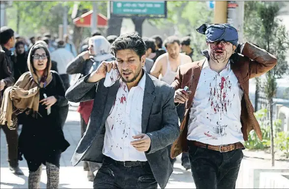  ?? OMAR SOBHANI / REUTERS ?? Algunos heridos por la explosión deambulan por la calle, en el centro de Kabul, cerca del lugar del atentado