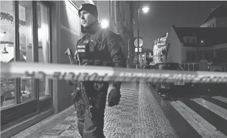  ?? JOHN MACDOUGALL/AFP VIA GETTY IMAGES ?? A police officer secures the area near the Charles University in central Prague on Thursday. A gunman killed more than a dozen people at the school, authoritie­s said.