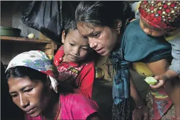  ?? Tim Bowden For The Times ?? HIM KUMARI BHANDARI, left, sister of Tejendra Bhandari, and other relatives look at a photograph of Subash Tamang and his family on July 15, 2017, at their home outside the village of Adhikarich­aur in Nepal.