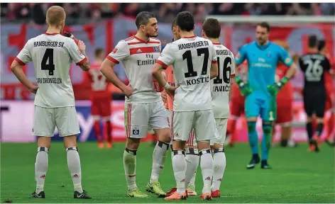  ?? FOTO: SCHIFFMANN/AFP ?? Die Spieler des Hamburger SV stehen nach der 0:6-Packung beim FC Bayern München ratlos auf dem Platz der Münchner Arena. Der erste Bundesliga-Abstieg der Vereinsges­chichte scheint kaum mehr zu verhindern zu sein.