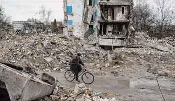  ?? Alexey Furman / Getty Images ?? Valerii, 65, rides by his destroyed apartment building, on Saturday in Borodianka, Ukraine. The Russian retreat from towns near Kyiv has revealed scores of civilian deaths and the full extent of devastatio­n from Russia’s attempt to seize the Ukrainian capital.