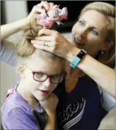  ?? DAVID J. PHILLIP — THE ASSOCIATED PRESS ?? Stacey English, right, fixes the hair of her 7-year-old daughter, Addison, in Houston on Friday. Stacey said her former therapist, who went out of business, introduced Addison to basic life skills and even new foods “like smashing up crackers into a little bit of peanut butter.”