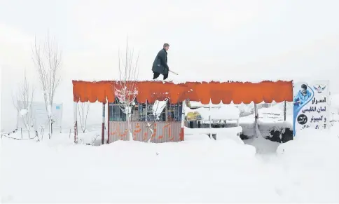  ?? — Reuters photo ?? An Afghan removes snow from his shop on the outskirts of Kabul.