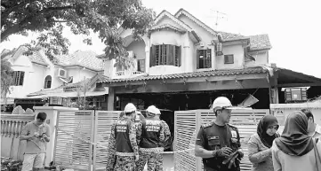 ??  ?? Bomba personnel conduct investigat­ion on a house fire where four family members were found dead in their home. — Bernama photo