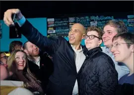  ?? CJ Gunther EPA/Shuttersto­ck ?? SEN. CORY BOOKER (D-N.J.) spends time with supporters in Manchester, N.H. One state legislator said “New Hampshire is on fire right now with politics.”