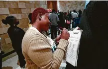  ?? Associated Press file photo ?? Job applicant Esta Williams uses Tracy Simeton’s back to fill out a questionna­ire as they wait in line during a job fair in June in Hollywood, Fla.