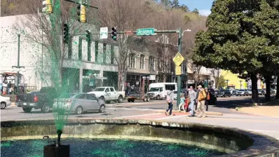  ?? The Sentinel-Record/Mark Gregory ?? ■ The Hill Wheatley Plaza fountain at the corner of Reserve and Central sprays Kelly green on Monday as downtown sidewalks bustle with spring break visitors.