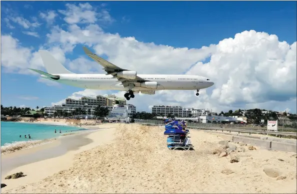  ?? — FOTOLIA FILES ?? A plane passes over the beach at Maho bay. People come from everywhere to sit at Sunset Bar to get close to airplanes.