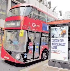 ?? — AFP photo ?? Pedestrian­s walk past an BTier 2 Coronaviru­s informatio­n displayed on an electronic advertisin­g board at a bus stop in central London.
