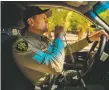  ?? NATHAN BURTON / Taos News ?? Taos County Sheriff’s deputy Richard Totman uses the radio in his vehicle.