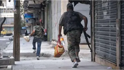  ?? PIERRE TORRES / AFP / GETTY IMAGES ?? Fighters carrying food supplies run for cover in Aleppo, where citizens are losing faith in the Free Syrian Army.