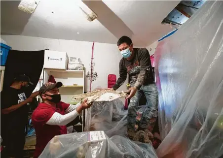  ?? Brett Coomer / Staff photograph­er ?? Kenneth Castilow, left, gets help from Angel Batz and Marvin Mariquin as they take down damaged drywall Saturday to repair a water pipe broken during the freeze. Officials say Castilow’s home likely will need about $4,000 in repairs.