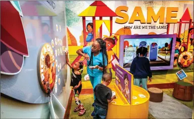  ?? (Special to the Democrat-Gazette/Arkansas Department of Parks, Heritage and Tourism, Kirk Jordan) ?? Jasmine Taylor Harris and her children Justice and Joshua place magnets on a wall at the new children’s gallery at Mosaic Templars Cultural Center while Pilar Primm explores different characters on a video screen. The gallery will celebrate its grand opening Saturday.