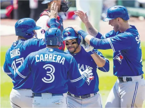  ?? JasonMiler/ Gett y Images ?? Base runners Ryan Goins, Ezequiel Carrera and Michael Saunders, right, congratula­te Devon Travis at home
plate after his grand slam off pitcher Trevor Bauer in the fourth against the Indians Sunday in Cleveland.