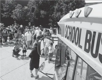  ?? MIKE CARROCCETT­O / OTTAWA CITIZEN ?? Kids and parents lined up outside Sir Guy Carleton High School for School Bus Awareness Day in late August. School buses will be on the road Tuesday and police remind drivers that failing to stop for a school bus with its lights flashing carries a $400...