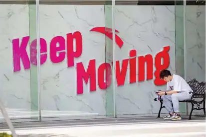  ?? — IC ?? A young man sits beside a wall carrying sportswear firm Anta’s slogan. Anta is the official partner of 2022 Beijing Winter Olympics.