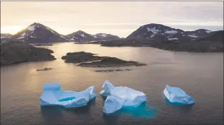  ?? Felipe Dana / Associated Press ?? Large icebergs float away as the sun rises near Kulusuk, Greenland. Scientists are hard at work, trying to understand the alarmingly rapid melting of the ice.