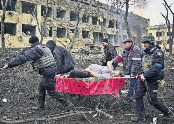  ?? ?? An injured pregnant woman is carried out of the shelled maternity hospital in Mariupol, above, while another expectant mother, clutching blankets, looks dazed, below