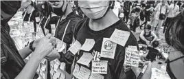  ?? ANTHONY KWAN/GETTY ?? Protesters stick notes on a “Human Lennon Wall” Sunday at the airport in Hong Kong.