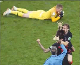  ?? The Associated Press ?? Croatia players Luka Modric and Mario Mandzukic celebrate with a coach as England goalkeeper Jordan Pickford looks on at the end of their World Cup semifinal in Moscow, Russia, on Wednesday. Croatia won 2-1 and will face France in Sunday’s final.