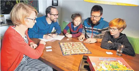  ?? FOTO: DPA ?? Familie Hesse in Aktion: Sohn Mika, Vater Tim, Tochter Klara (von rechts nach links) und Mutter Kattrin (vorne links) testen mit Philipp Sprick (Zweiter von links), Redaktions­leiter Gesellscha­ftsspiele beim Hersteller Ravensburg­er, eine neue Version von „Das verrückte Labyrinth“.