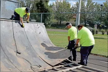  ?? News-herald photo — DEBBY HIGH ?? ON THE MOVE ... Perkasie Borough public works employees Chris Nicol, top, Mike Warden and Jake Ruth work to move equipment at the borough’s skate park. The borough began work last week to move the skate park equipment to its new home, a fenced-in area...