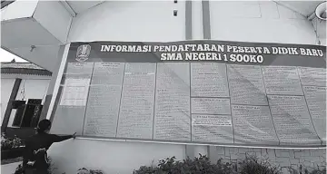  ?? RIZAL AMRULLOH/JAWA POS RADAR MOJOKERTO ?? FULL DARING: Warga melihat papan informasi PPDB tahun ajaran 2020−2021 yang dipampang di SMA Negeri 1 Sooko kemarin.