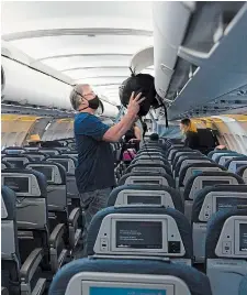  ?? JONATHAN HAYWARD THE CANADIAN PRESS FILE PHOTO ?? A passenger is seen wearing a mask as he boards a flight from Vancouver to Calgary. Alex Scordas is worried about the lack of public education on proper use of face coverings and hand hygiene during the pandemic.