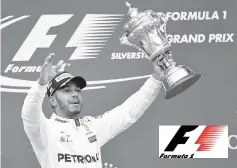  ??  ?? Winner Mercedes’ British driver Lewis Hamilton celebrates with his trophy on the podium after the British Formula One Grand Prix at the Silverston­e motor racing circuit in Silverston­e, central England. - AFP photo