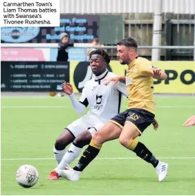  ??  ?? Carmarthen Town’s Liam Thomas battles with Swansea’s Tivonee Rushesha.