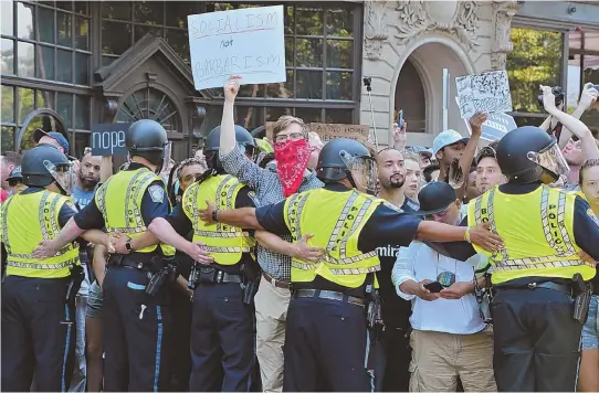  ?? STAFF PHOTO BY CHRIS CHRISTO ?? KEEPING THE PEACE: Police hold back protesters on Boylston Street, as they wait for Boston Free Speech Rally speakers to be transporte­d from Boston Common.