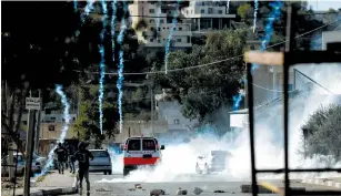  ?? (Mohamad Torokman/Reuters) ?? TEAR-GAS CANNISTERS are fired by IDF troops toward Palestinia­ns during clashes in the West Bank village of Kusra yesterday.