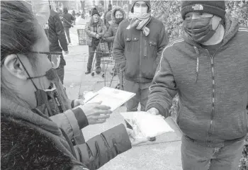  ?? EDUARDO MUNOZ ALVAREZ/AP ?? Governors are hesitant to add federal vaccinatio­n sites, saying they need doses instead. Above, volunteers hand out vaccine informatio­n to visitors of a community center Saturday in the Brooklyn borough of New York.