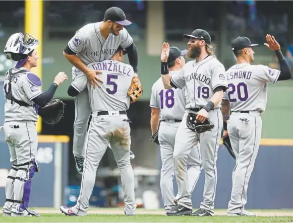  ??  ?? Nolan Arenado gets a lift from teammate Carlos Gonzalez as the Rockies celebrate their 5-4 victory in 11 innings against the Brewers on Sunday in Milwaukee.