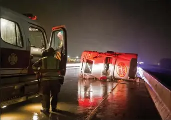  ?? Staff photo by Adam Sacasa ?? An 18-wheeler lies overturned on a bridge across East Ninth Street on Arkansas Highway 245 during a storm Tuesday night. Heavy winds and rain caused dangerous driving conditions.