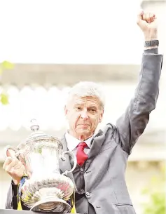  ?? — AFP photo ?? In this file photo taken on May 31, 2015 Arsenal’s French manager Arsene Wenger holds the trophy from the top deck of an open-topped bus during the Arsenal victory parade in London on May 31, 2015, following their win in the English FA Cup final...