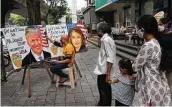  ?? Rajanish Kakade / Associated Press ?? Pedestrian­s in Mumbai, India, look at poster art that carries get-well messages for the Trumps on Friday.