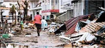  ?? MARTIN BUREAU/GETTY-AFP ?? A woman carries supplies Monday in Marigot, St. Martin. The island was one of the hardest hit by Hurricane Irma.