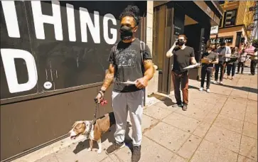  ?? Al Seib Los Angeles Times ?? STEVEN WHITE, 28, with his dog, Doja, waits in line for a COVID-19 vaccinatio­n Wednesday at the Million Dollar Theater in downtown Los Angeles. “I feel like it kind of grew us up a little bit,” he said of the pandemic.