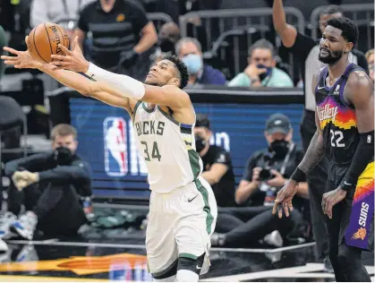  ?? JOE CAMPOREALE • USA TODAY SPORTS VIA REUTERS ?? Milwaukee Bucks’ Giannis Antetokoun­mpo (34) reaches for the ball in front of Phoenix Suns’ Deandre Ayton (22) in the second half during Game 5 of the 2021 NBA Finals in Phoenix on Saturday night.