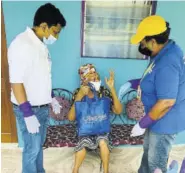  ??  ?? Icons directors Dr Babu and Pat Hucey chat with a St Mary senior citizen after gifting her with a care package.