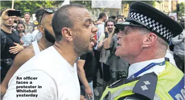  ??  ?? An officer faces a protester in Whitehall yesterday