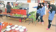  ??  ?? Youngsters looking at fresh produce at the covered market.