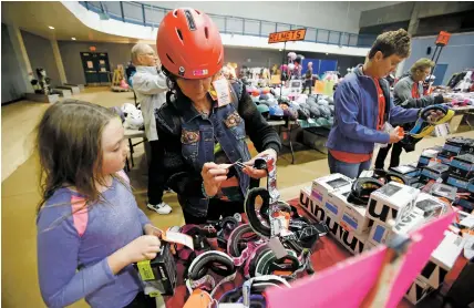  ?? LUIS SÁNCHEZ SATURNO/THE NEW MEXICAN ?? Jeannette Kelly of Santa Fe tries on goggles with her daughter Katie Mooney, 9, on Friday at the Ski Swap at the Genoveva Chavez Community Center. The event is the annual fundraiser for the Santa Fe Ski Team.