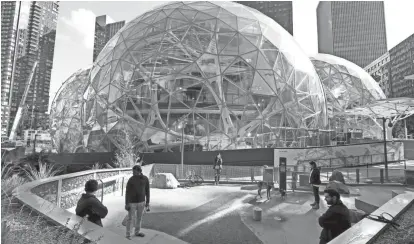  ?? ELAINE THOMPSON/AP ?? Large spheres take shape in front of an existing Amazon building, adjacent to a small dog park provided by the company, in Seattle.